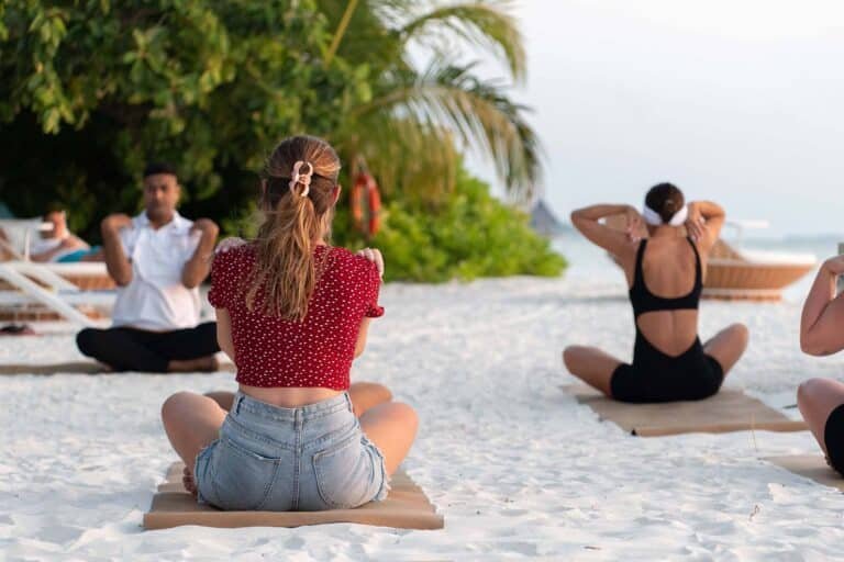 Guests participating in International Women’s Day sunset yoga session at Dhoni Bar Beach, Canareef Resort Maldives.
