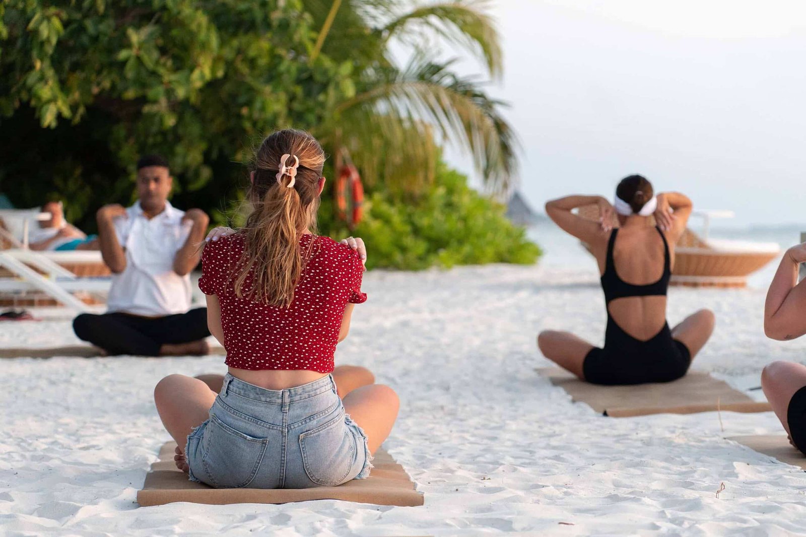 Guests participating in International Women’s Day sunset yoga session at Dhoni Bar Beach, Canareef Resort Maldives.
